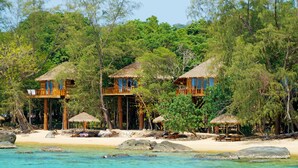 A beachfront property with thatched-roof cabins, a sandy beach, and a clear view of the ocean. - Tree House Bungalows Resort (Koh Rong)