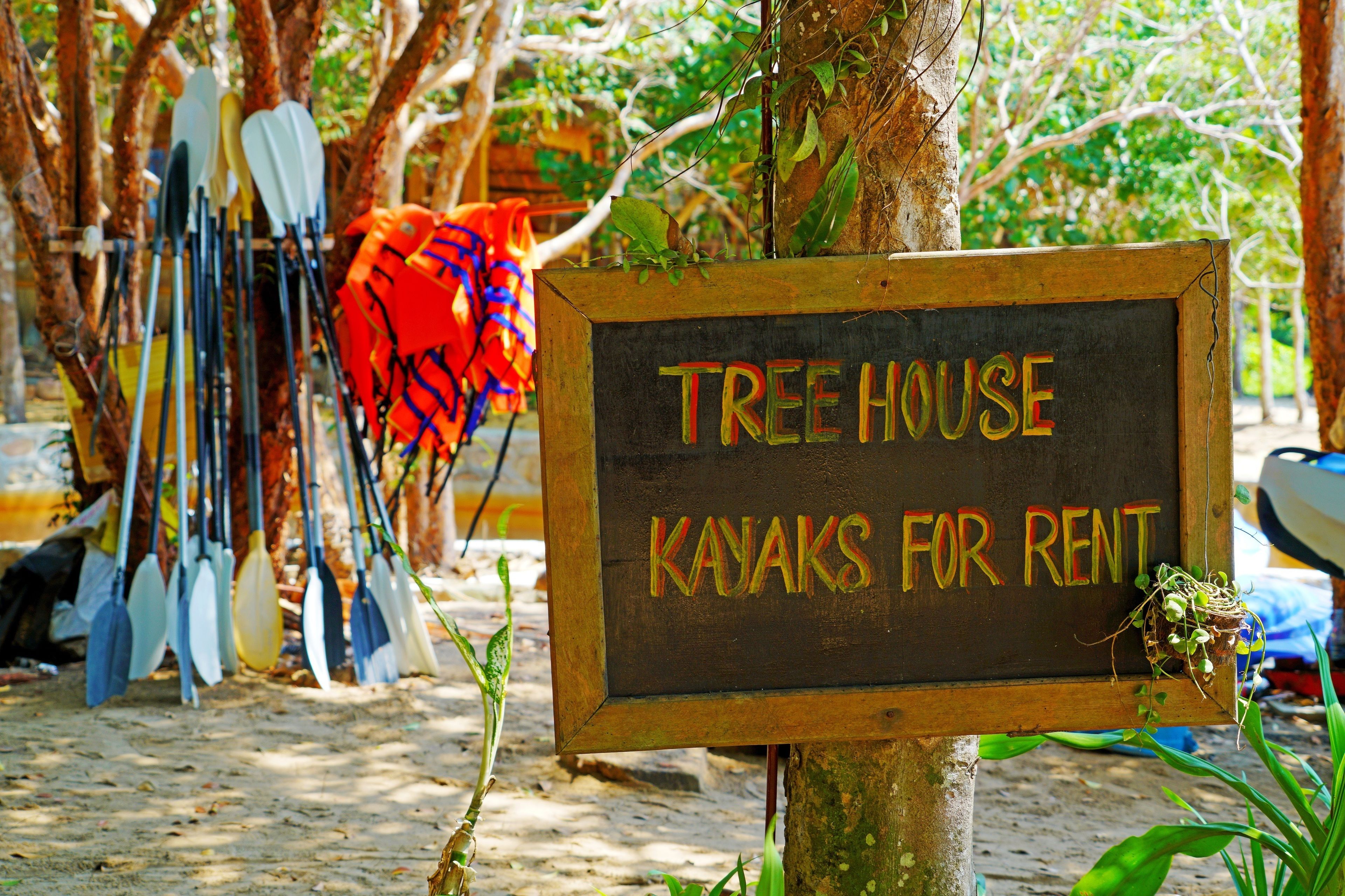 A sign for a treehouse rental service with kayaks.