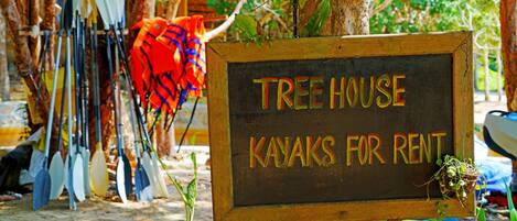 A sign for a treehouse rental service with kayaks.