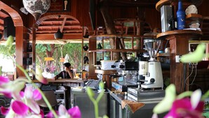 A coffee shop with a wooden interior, a coffee machine, and a person working behind the counter. - Tree House Bungalows Resort (Koh Rong)