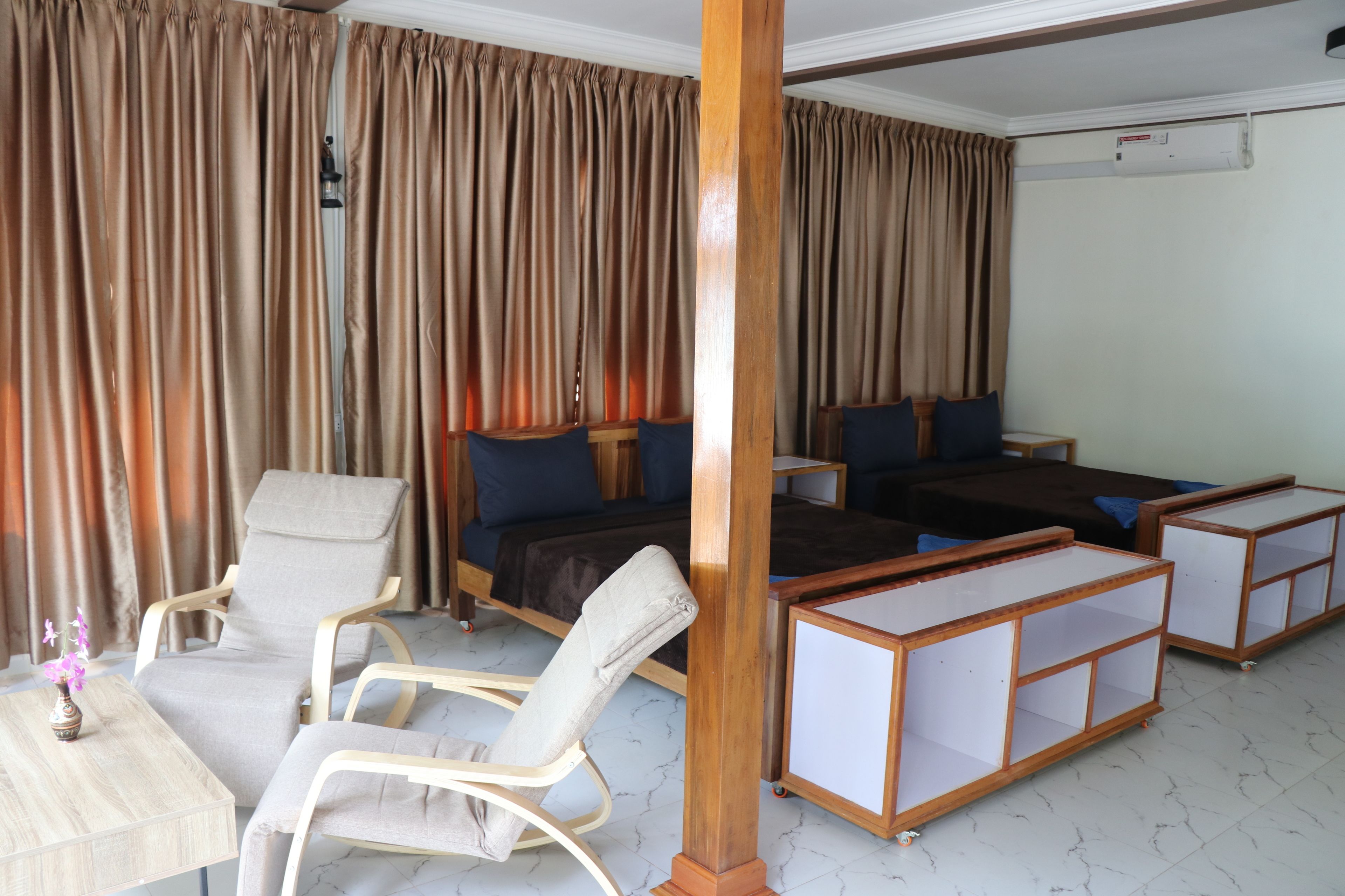 A hotel room with a bed, two sofas, a chair, a small table, and a wooden cabinet.
