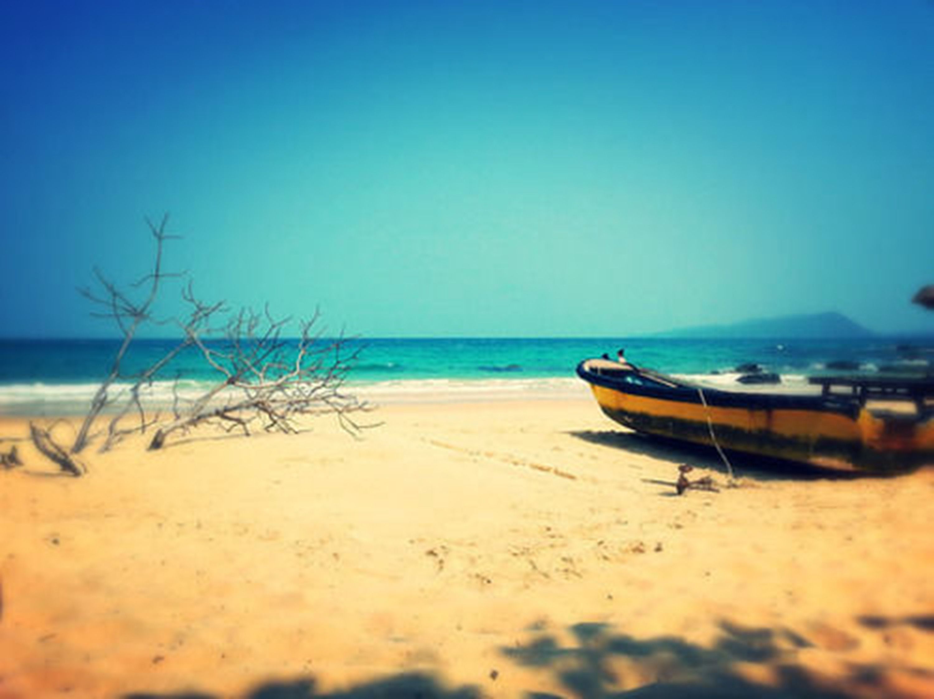 A beach with a boat on the sand and a mountain in the background.