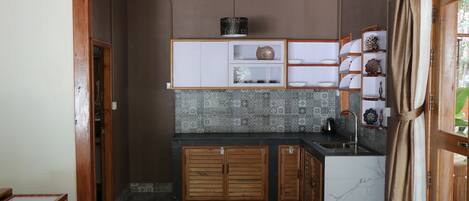 A compact kitchen with wooden cabinets, a built-in sink, and patterned backsplash tiles.