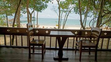 Enjoy a serene beach view from this deck, featuring a table and two chairs.