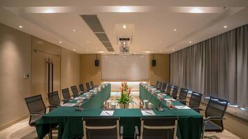 A conference room with a long table, chairs, and a projector screen.