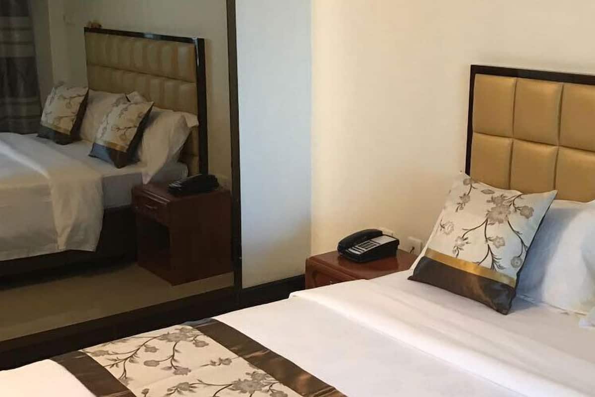 Een hotelkamer met een groot bed, een nachtkastje, een telefoon en een spiegel.