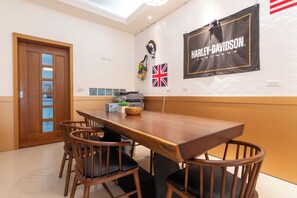 A dining area with a wooden table and chairs, a Harley-Davidson banner, and a Union Jack flag. - Tu Wei 192 (Zhuangwei)