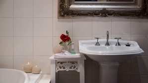 A bathroom with a white bathtub, a white pedestal sink with three faucets, and a mirror above the sink. - Impressions Studio (Daylesford)