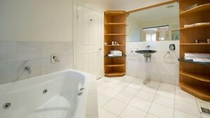 Un baño con bañera, lavamanos y estantes de madera.