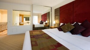 Habitación de hotel con una cama grande, un espejo, un escritorio y vista al baño.