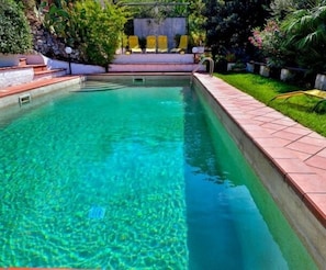 Una piscina al aire libre de temporada, sombrillas