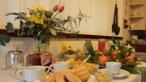 Una mesa de desayuno con pasteles, una cafetera y una bandeja de frutas.