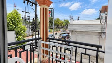 Un balcone con vista su una strada, un negozio di alimentari 7-Eleven e un pavimento piastrellato.