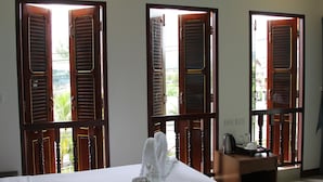Una habitación de hotel con cama, mesita de noche y ventana con contraventanas de madera.