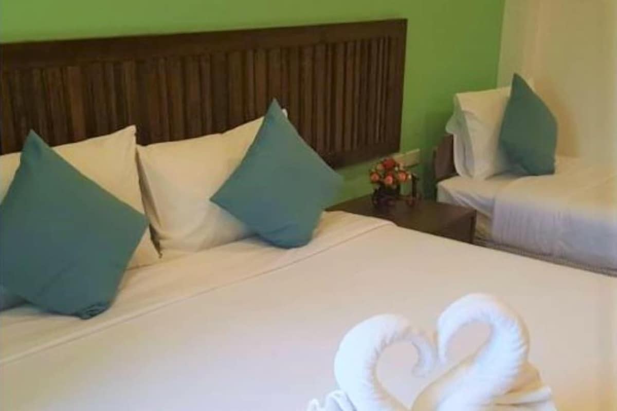 Ein Hotelzimmer mit einem Bett, Kissen, einem Kopfteil und einem kleinen Tisch mit einem Blumenstrauß.
