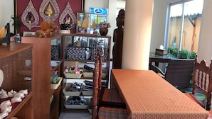 Una habitación con una mesa de madera, estantes con diversos objetos y una gran estatua.