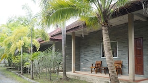 A building with a stone facade, a tiled roof, and a porch with two wooden chairs.