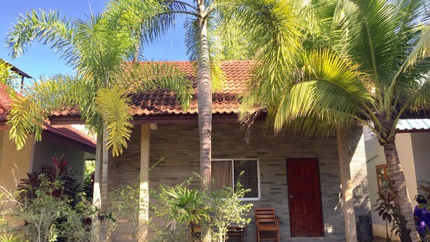 A house with a tiled roof, a wooden door, and a small porch with chairs.