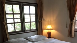 A hotel room with a bed, two pillows, a lamp, and a window with curtains.