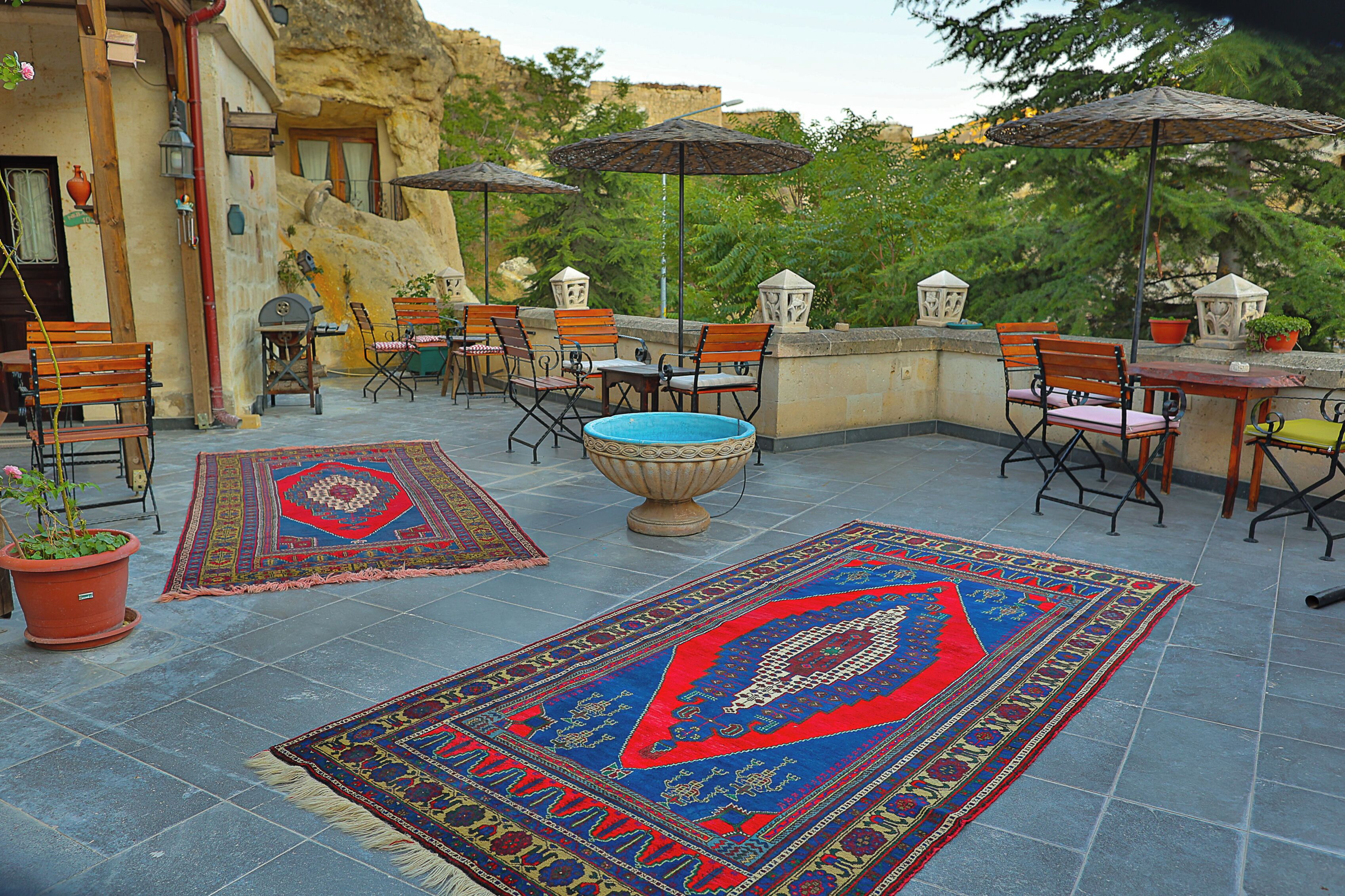 An outdoor patio with seating, umbrellas, and decorative rugs.