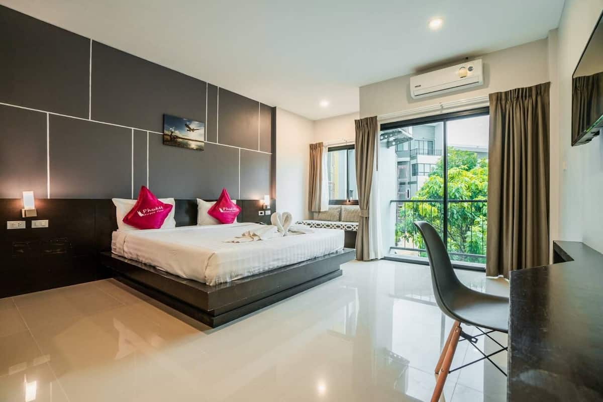 A modern hotel room with a large bed, a desk, and a balcony with a view.