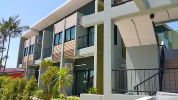 Un hotel de varios pisos con balcones, unidades de aire acondicionado y una escalera.