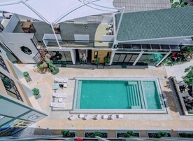 Un edificio de varios niveles con piscina central, zonas de estar al aire libre y un porche cubierto.