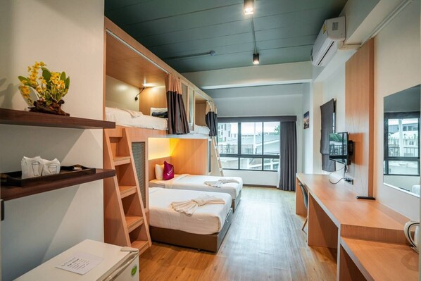 Habitación de hotel moderna con literas, un escritorio, un televisor y vistas a la ciudad.