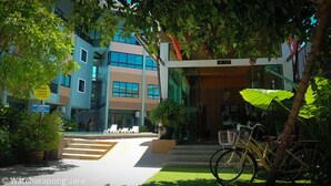 Un edificio moderno con fachada de vidrio, una escalera que lleva a la entrada y una bicicleta estacionada afuera.