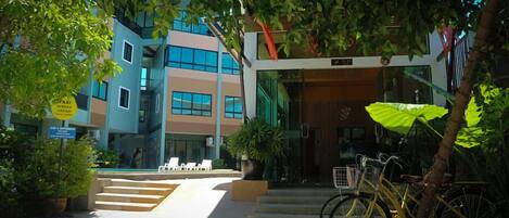 Un edificio moderno con fachada de vidrio, una escalera que lleva a la entrada y una bicicleta estacionada afuera.