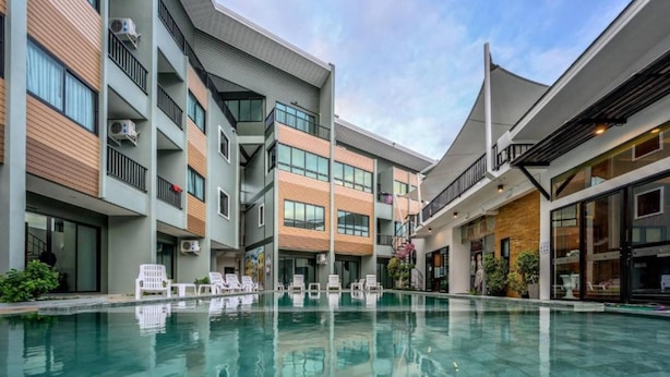 Un hotel moderno con piscina central, varios balcones y una combinación de fachadas de madera y hormigón.