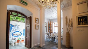 A hallway with a chandelier, framed artwork, and a large vase with pampas grass. - Katina Bozcaada (Bozcaada)