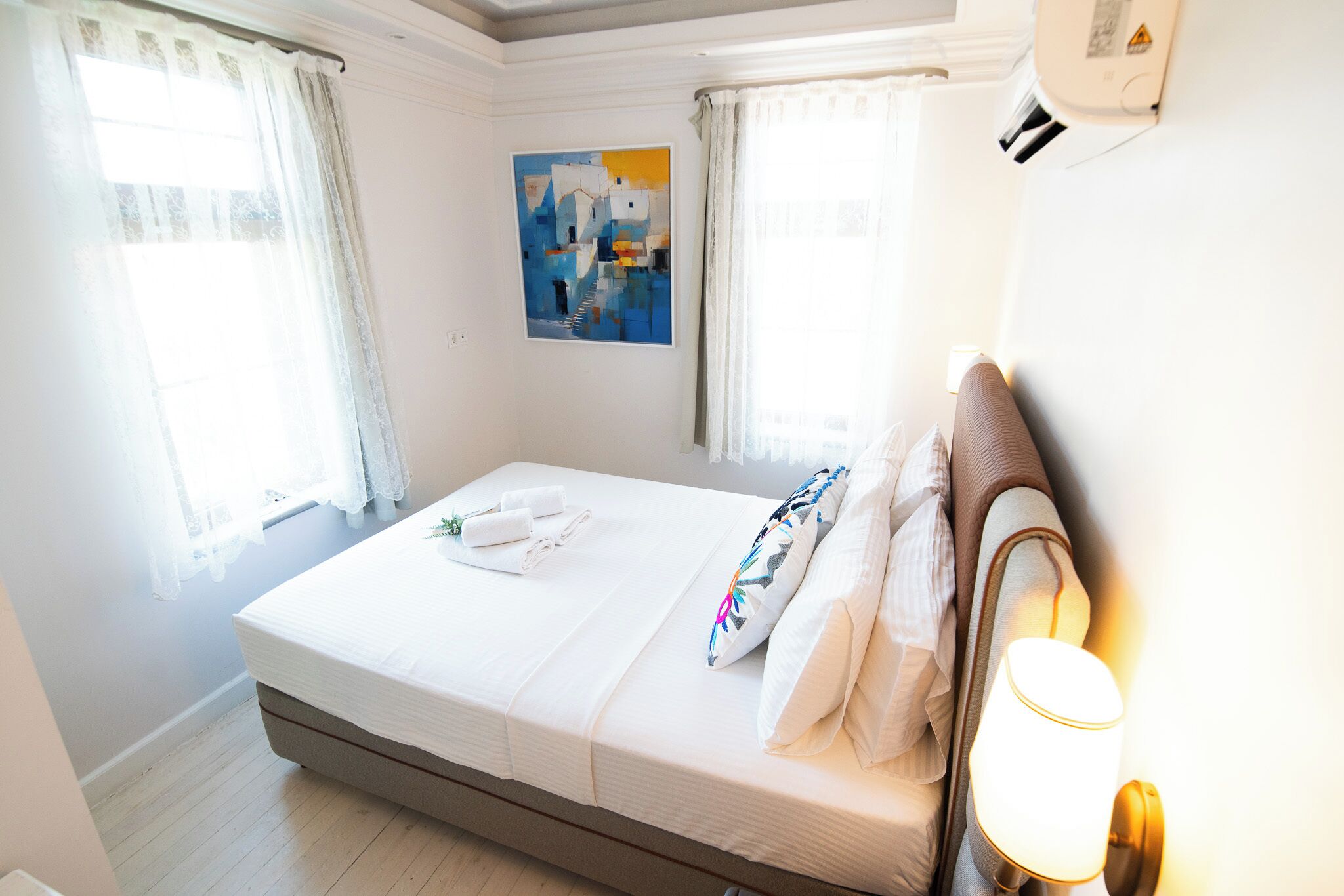 Una habitación de hotel con una cama, un cuadro en la pared y una ventana con cortinas.