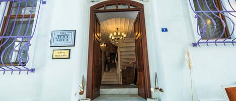 A building entrance with a wooden door, a chandelier, and two signs indicating the name 'Katina Bozcaada.'