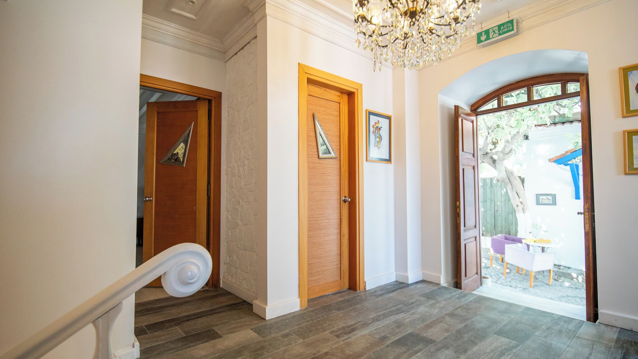 A hallway with a wooden door, a staircase, and a chandelier.