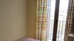 A room with a bed, a window with curtains, and a view of the outside. - Pensión Mollo (Madrid)