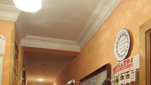A hotel hallway with a bulletin board displaying various advertisements and a clock on the wall. - Pensión Mollo (Madrid)