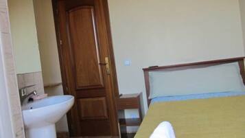 Une chambre à coucher avec un lit, une porte en bois et un lavabo blanc.