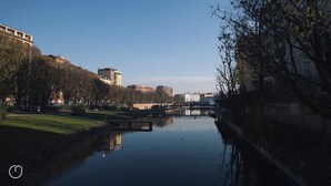 A calm river with a bridge, buildings, and trees along the banks. - Italianway   - Alessi (Milan)