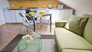 A compact living space with a kitchenette, a dining area, and a sofa. - Italianway   - Alessi (Milan)
