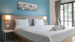 A hotel room with a large bed, two bedside lamps, a wall-mounted artwork, and a view through a window with curtains. - S2 Airport Residence (Sa Khu)