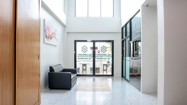A spacious lobby with a high ceiling, a reception desk, and a seating area with a sofa. - S2 Airport Residence (Sa Khu)