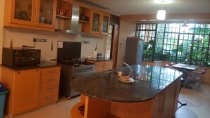 Una cucina con mobili in legno, un fornello, un lavello e una finestra con vista sul verde.