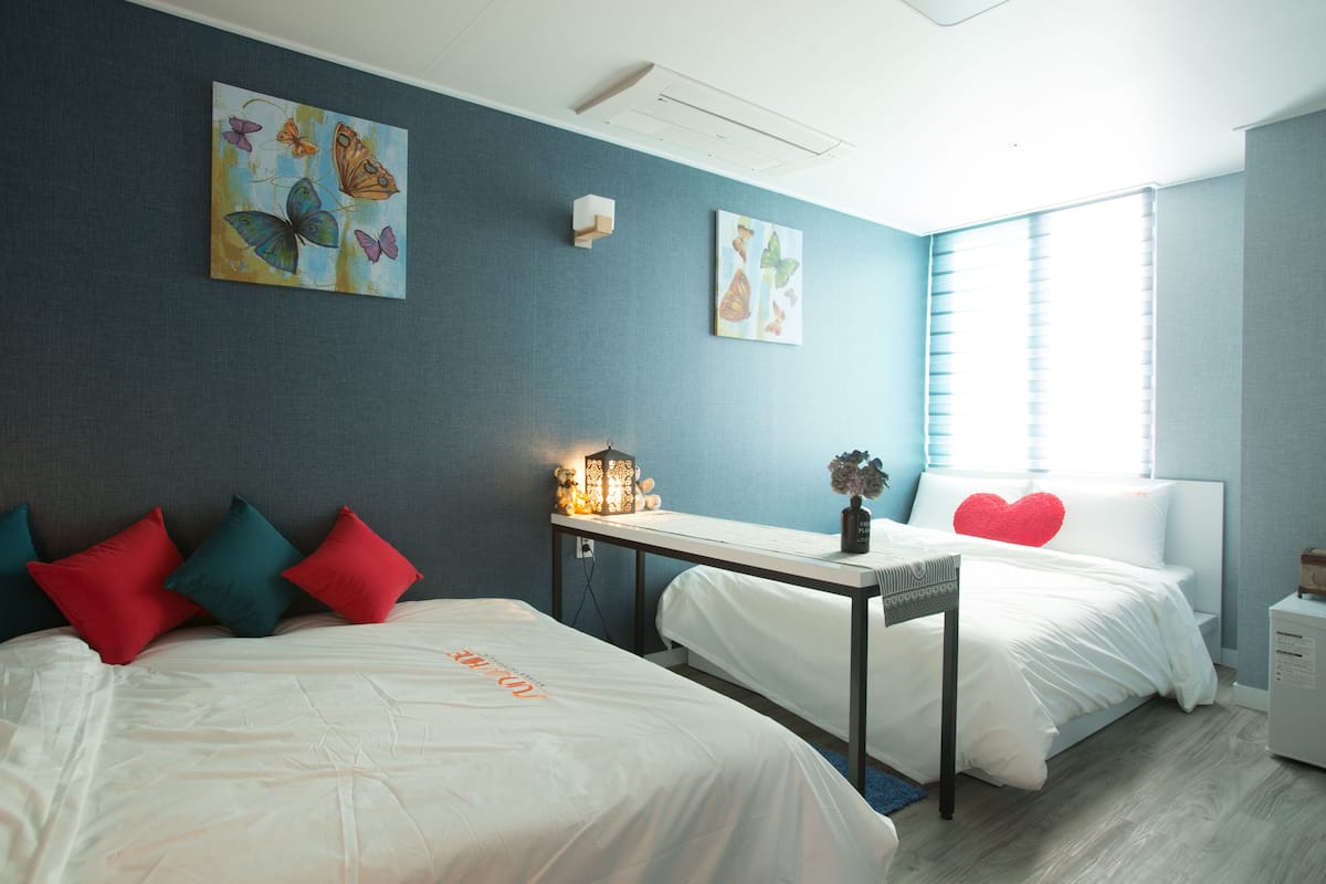 Een hotelkamer met twee bedden, een bureau en kunstwerken aan de wanden.