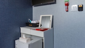 Une chambre moderne équipée d’un bureau, d’un téléviseur fixé au mur, d’une poubelle et d’un interrupteur fixé au mur.
