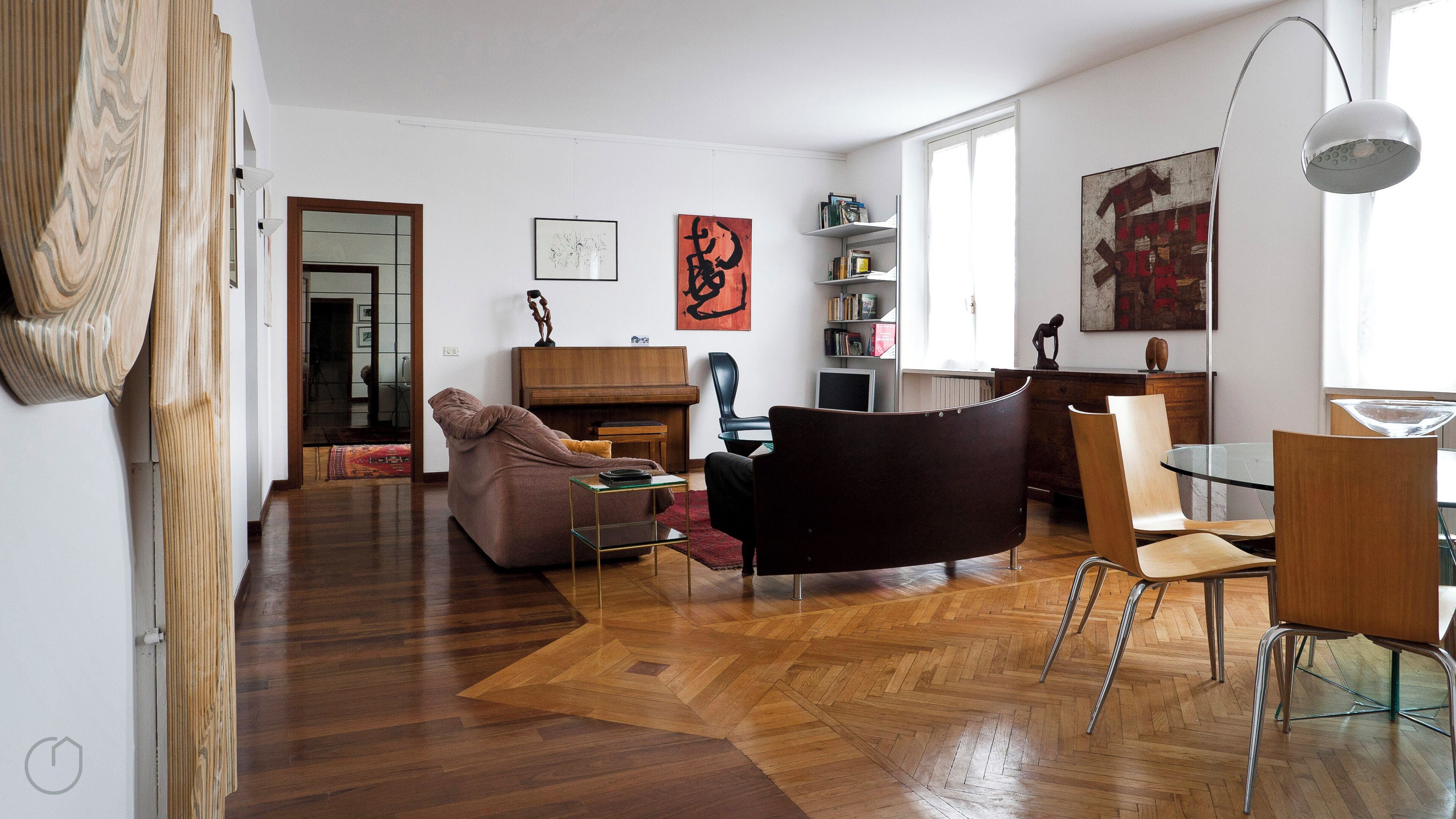 A spacious living room with a piano, a glass dining table, and modern furniture.