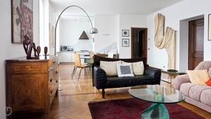 Un soggiorno moderno con un divano in pelle nera, un tavolino in vetro e un tappeto rosso. Sullo sfondo, un mobile in legno e un'area pranzo.