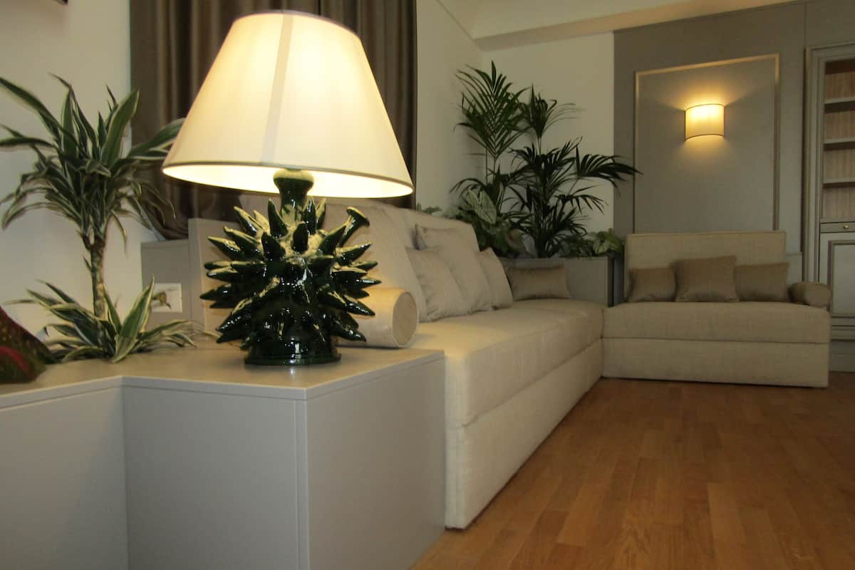 A living room with a white sofa, a lamp, and several potted plants.