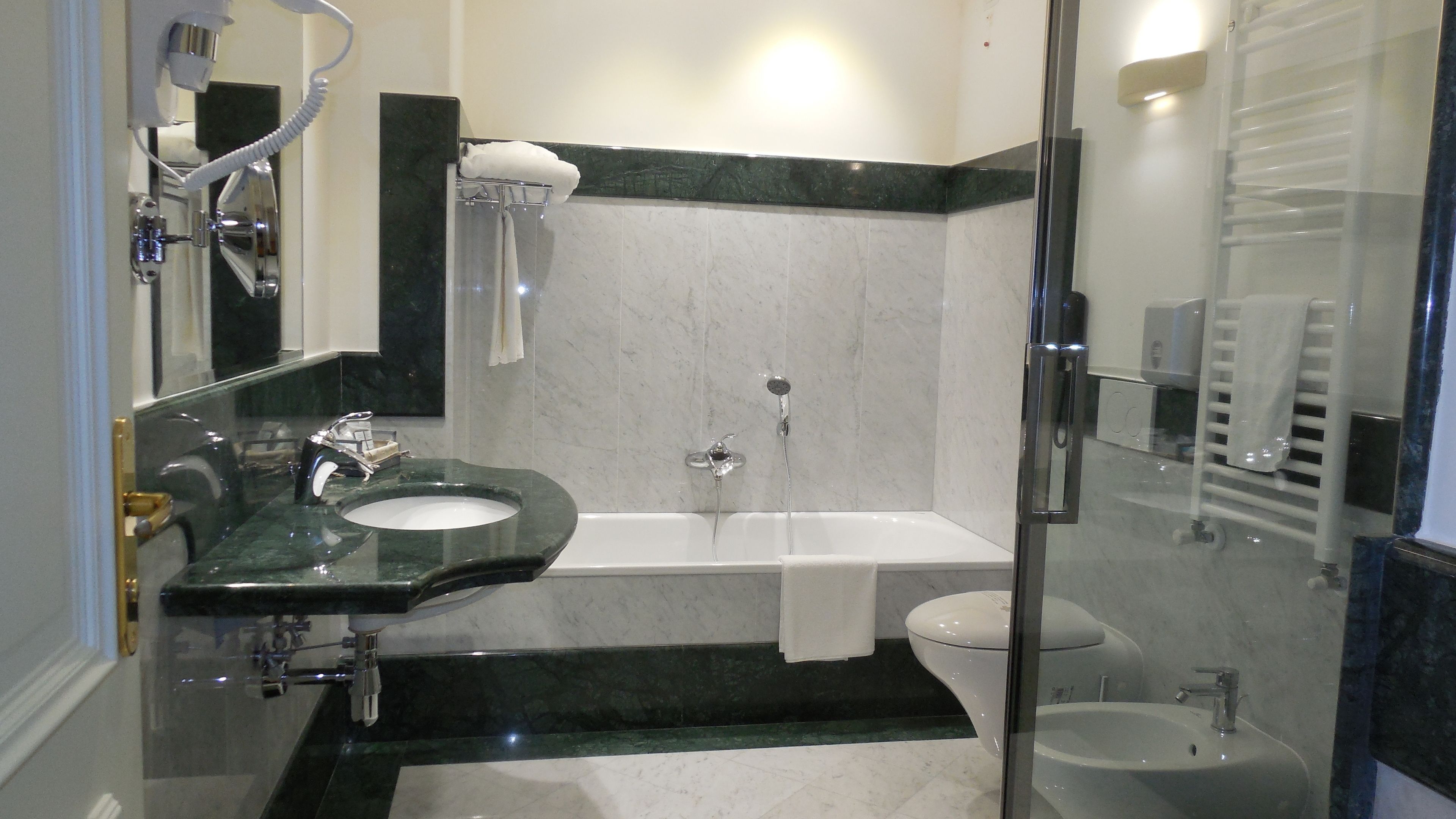 Un baño moderno con ducha envuelta en cristal, tocador con lavamanos y un inodoro.