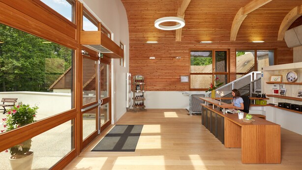 A modern kitchen with wooden beams, large windows, and a view of the outdoors. - Hôtel Centre Port-Royal (Saint-Lambert)